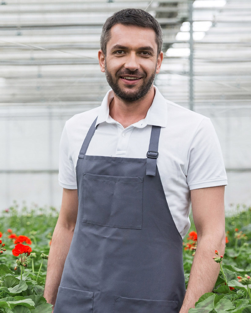 cheerful-young-man-standing-in-greenhouse-near-pla-P56ND5C.jpg